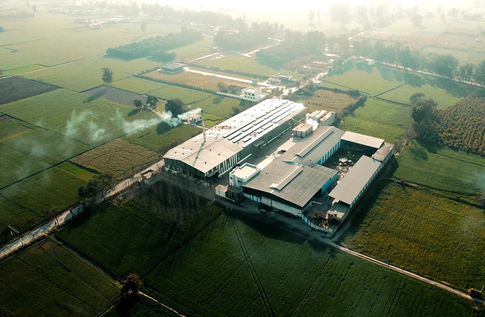The Artis Laminates plant seen from above at close range, steam rising from the press hall